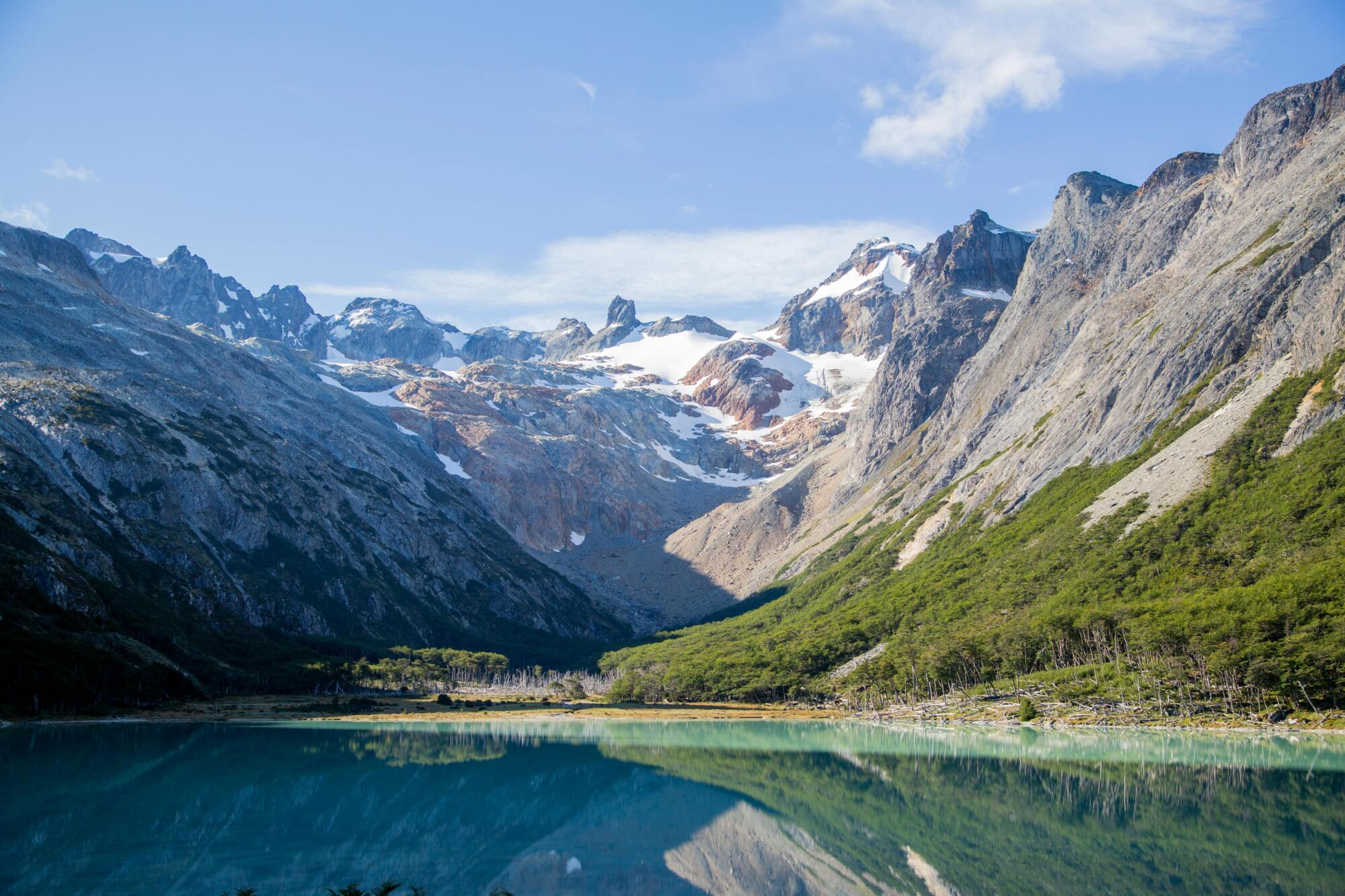 A tranquil mountain lake reflecting snow-capped peaks under a clear blue sky, perfect for nature lovers.