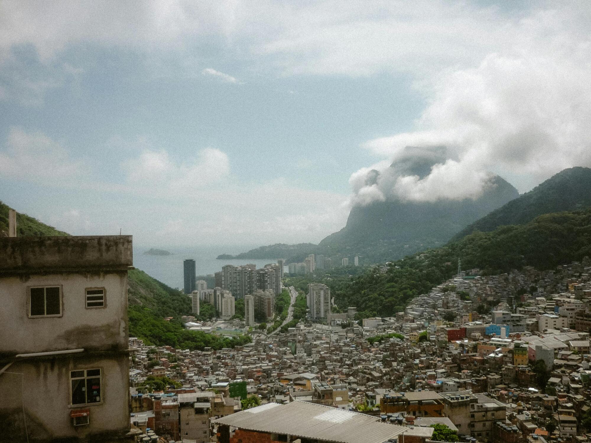 Aerial view of Rio de Janeiro cityscape with mountains and clouds in the background.